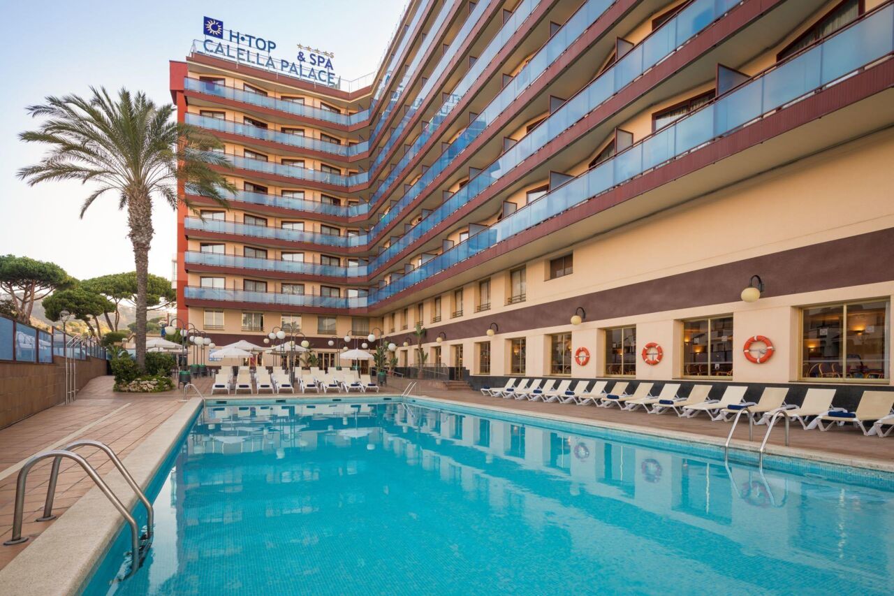 Außenpool mit Liegestühlen vor dem mehrstöckigen Hotel